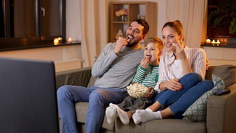 Familie schaut während dem Popcorn essen Fernseher