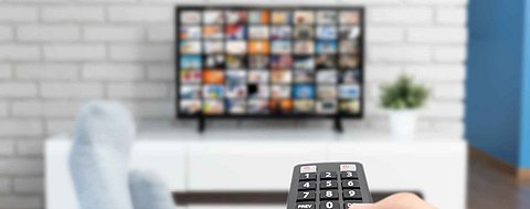 Mensch bedient Fernbedienung von einem Fernseher