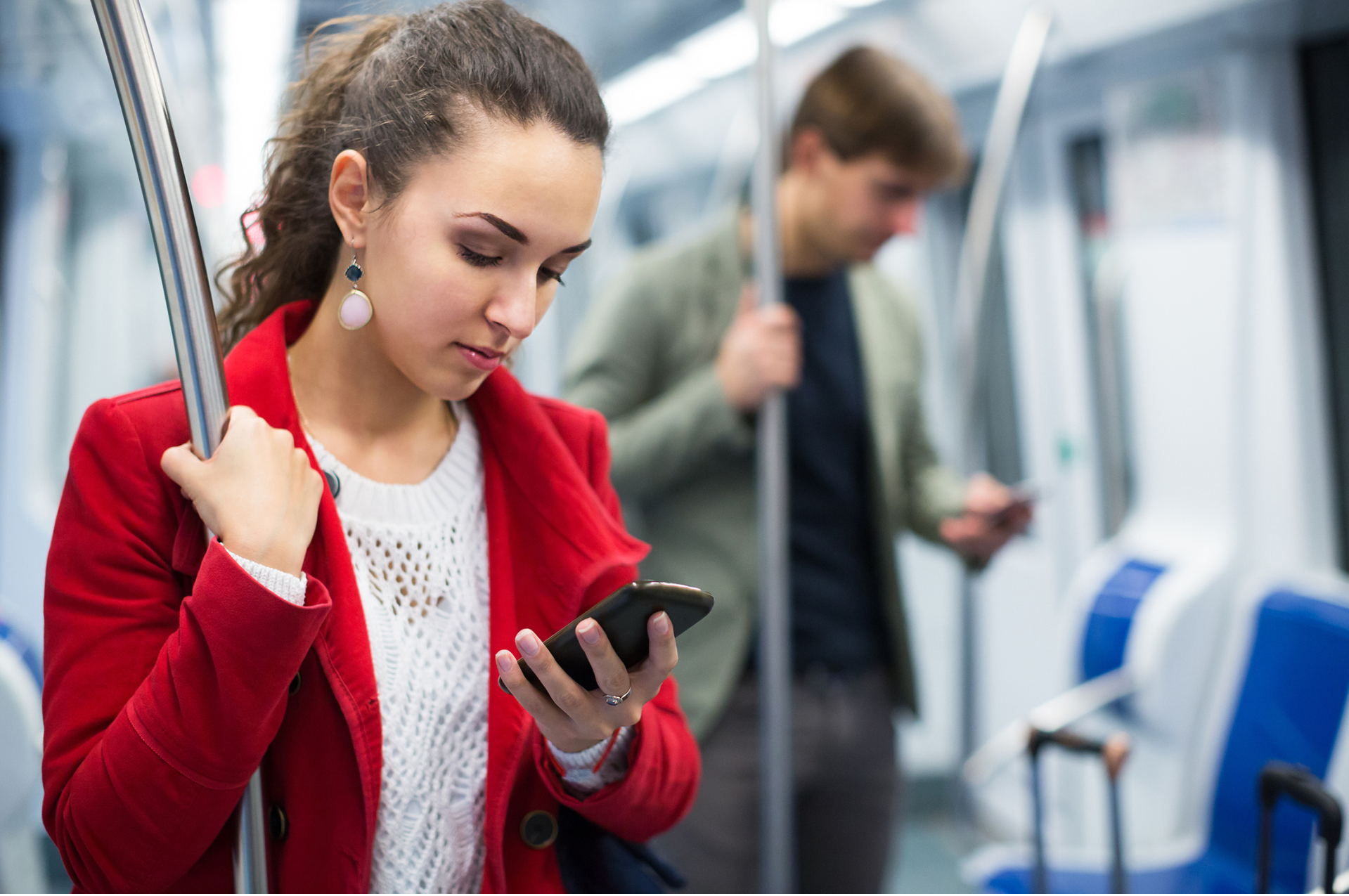 eine frau steht in der bahn und schaut auf ihr handy